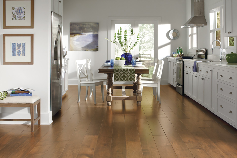 hardwood flooring in kitchen with white kitchen cabinets, natural furniture, and decor.